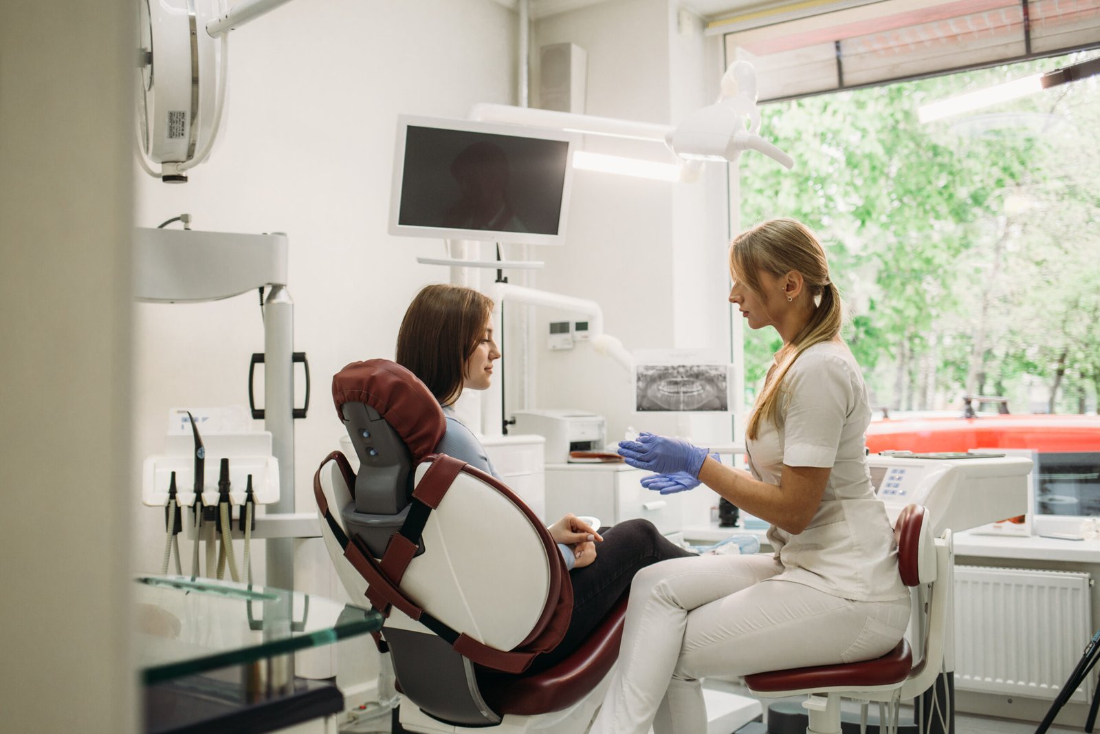woman holds aligners in dentistry while sitting in dental chair.