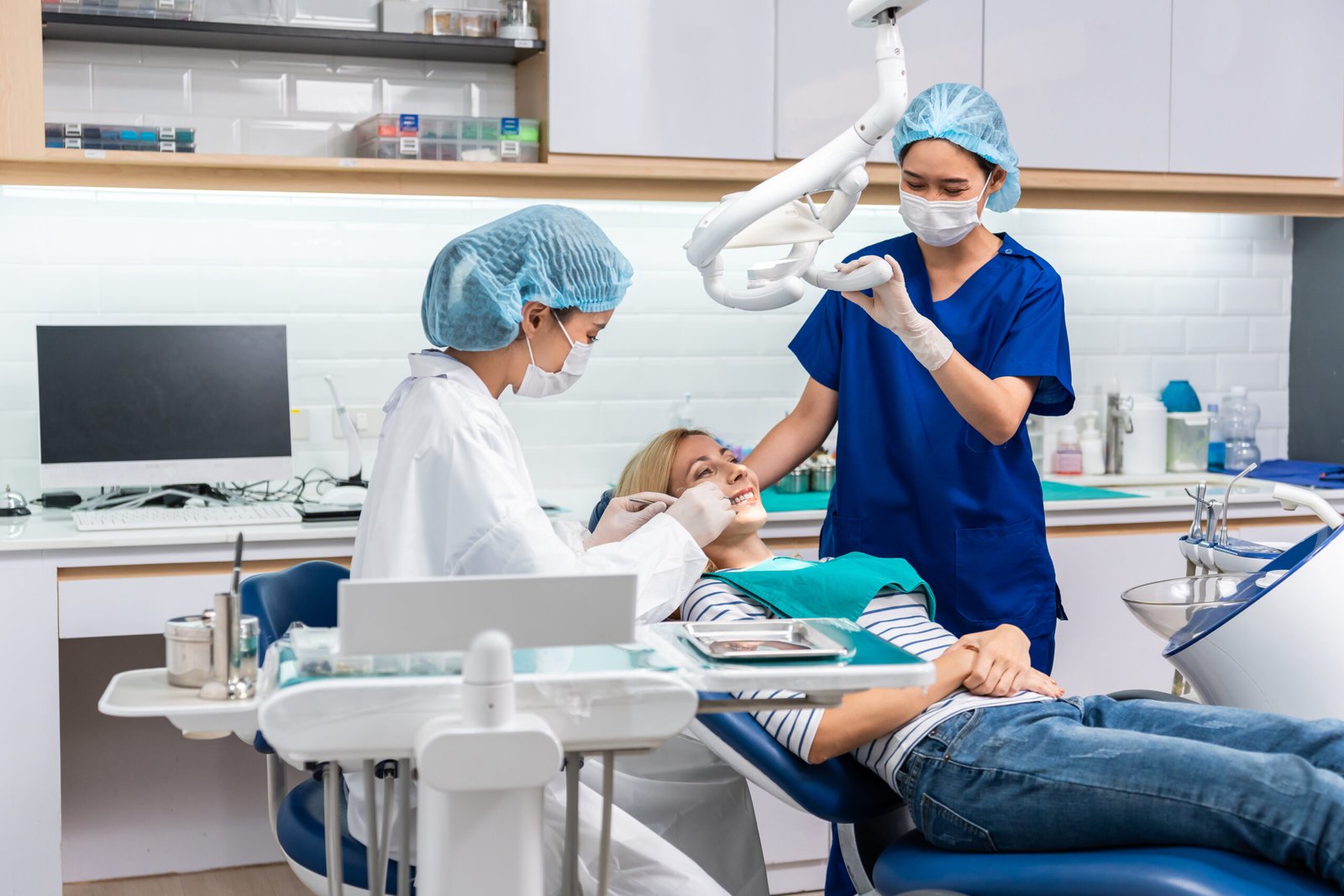 Female dentist examine tooth to Caucasian girl at dental health clinic. Attractive woman patient lying on dental chair get dental treatment from doctor during procedure appointment service in hospital